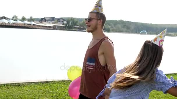 湖の背景にシャボン玉を吹く若いカップル. — ストック動画