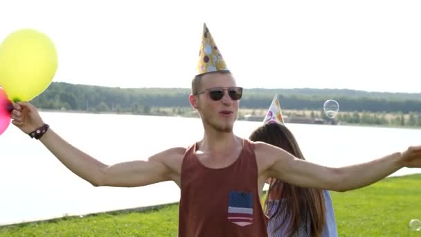 Young couple blowing soap-bubbles on the lake background. — Stock Video