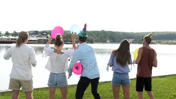 Unga groupe människor blåser såpbubblor på sjön bakgrunden. — Stockvideo