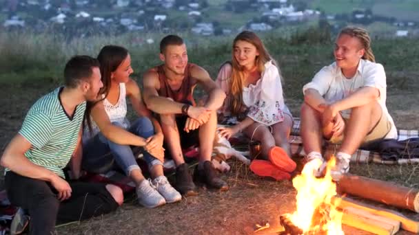 Ομάδα φίλων να καθίσει δίπλα σε ένα campfire με ζεστά ροφήματα και να μιλήσουμε — Αρχείο Βίντεο