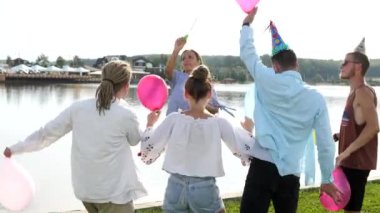 Göl özgeçmişlerine sabun köpüğü üfleme insanların genç groupe arka görünümü.