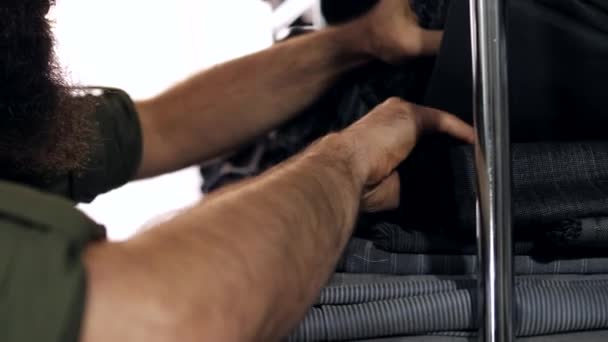 Kleermakers handen het kiezen van een grijze stof in een entrepot van het weefsel. Close-up. — Stockvideo