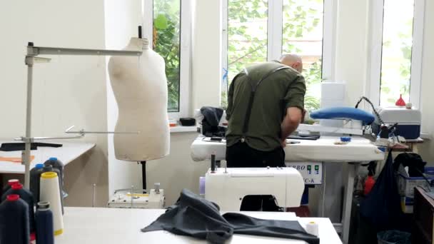 Een kleermaker in een workshop naaien op het werk. Achteraanzicht. — Stockvideo