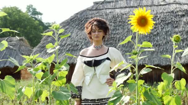Een Oekraïense meisje draait met een boeket in haar hand in de buurt van de zonnebloemen. — Stockvideo