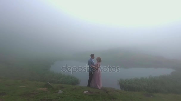 Vista aérea. Pareja amorosa cerca del lago en las montañas. — Vídeo de stock