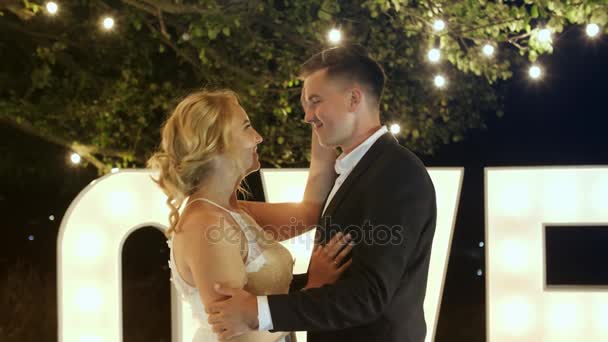 Jovem casal apaixonado em vestidos de noite estão dançando perto de cartas de luz do amor . — Vídeo de Stock