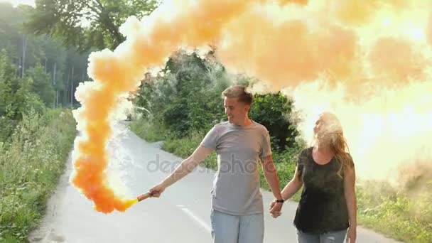 Casal feliz andando na estrada da floresta com bombas de fumaça — Vídeo de Stock