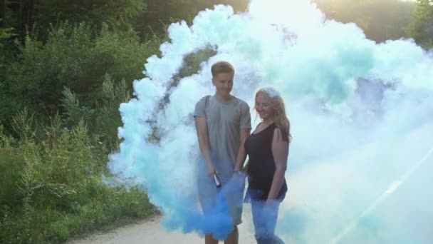 Pareja feliz caminando por el camino del bosque con bombas de humo — Vídeo de stock