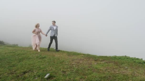 Pareja de lujo caminando en el prado de montaña en el fondo de la niebla — Vídeos de Stock