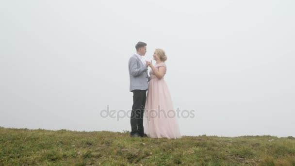 Primer plano. Pareja de lujo en vestidos de noche se abrazan en el prado de la montaña — Vídeos de Stock