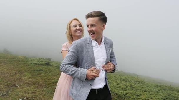 Pareja de lujo caminando en el prado de montaña en el fondo de la niebla — Vídeos de Stock