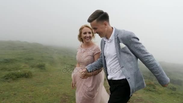 Розкішна пара біжить на гірському лузі на тлі туману — стокове відео