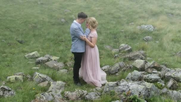 Le couple se tient au milieu des pierres dans la prairie et profite l'un de l'autre — Video