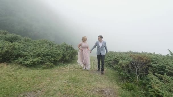 Luxe koppel loopt op de bergweide op de achtergrond van de mist — Stockvideo
