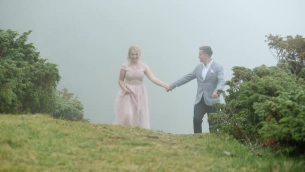 Pareja de lujo caminando en el prado de montaña en el fondo de la niebla — Vídeos de Stock