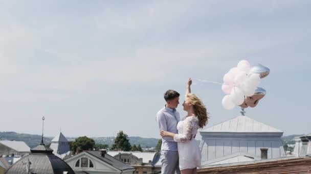 Para, trzymając kilka balonów na przytulanie rooftoop i cieszy się wzajemnie. — Wideo stockowe