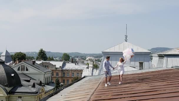 Ζευγάρι κρατώντας μερικά μπαλόνια και τα πόδια με το rooftoop. — Αρχείο Βίντεο