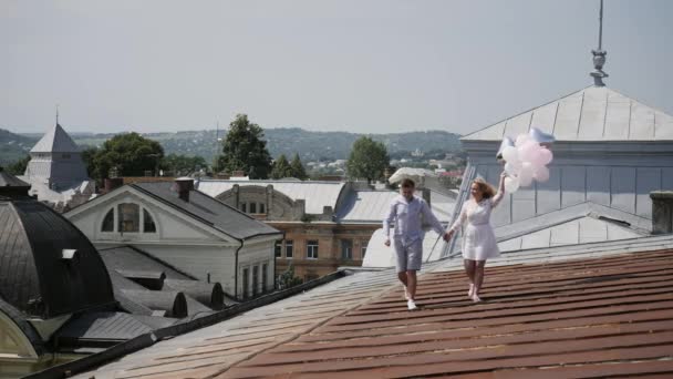 Couple tenant quelques ballons et marchant sur le toit . — Video