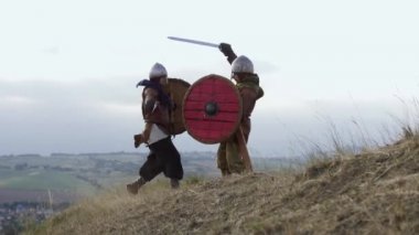 İki savaşçı Viking kılıç ve kalkanlar ile savaşıyoruz çayırda.