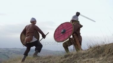 İki savaşçı Viking kılıç ve kalkanlar ile savaşıyoruz çayırda.