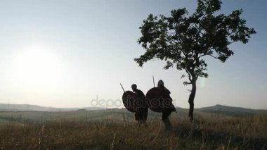 Siluetleri Viking savaşçıların saldırı sırasında kavga ediyorlar. Contre-jour