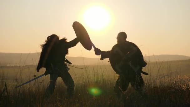 Siluetas de guerreros vikingos están luchando con espadas y escudos. Contre-jour — Vídeo de stock