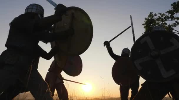 Sylwetki wojowników Wikingów, walka na miecze, tarcze. Contre jour — Wideo stockowe