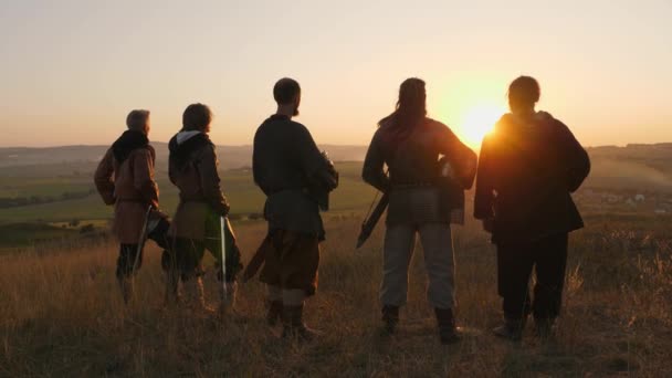 Guerreros vikingos se paran en el campo y miran la hermosa puesta de sol en el campo de batalla — Vídeo de stock