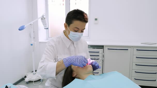 O dentista coloca o expansor de boca para uma linda garota no consultório odontológico . — Vídeo de Stock
