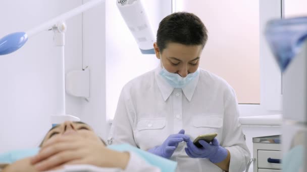 El dentista utiliza un teléfono inteligente . — Vídeo de stock