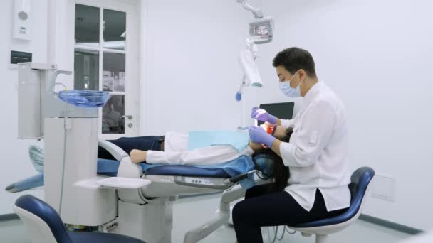 Mujer consiguiendo blanqueamiento UV en la oficina de dentistas por una máquina ultravioleta . — Vídeo de stock