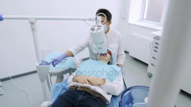 Kadın UV beyazlatma diş hekimleri ofiste bir ultra violet makine tarafından almak..