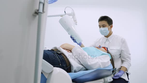 Mujer consiguiendo blanqueamiento UV en la oficina de dentistas por una máquina ultravioleta . — Vídeos de Stock