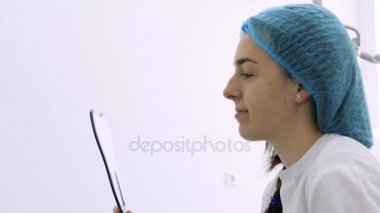 Genç hastaya dişlerini diş hekimleri ofiste aynaya bakarak.