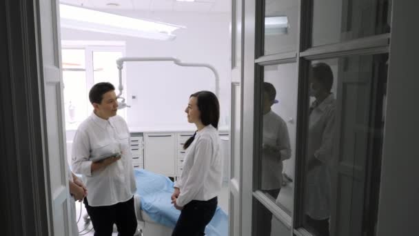 Dentist talking with young female patient in at the dentist clinic. — Stock Video