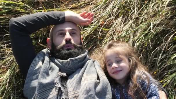 Pai e sua filha deitados na grama no prado . — Vídeo de Stock