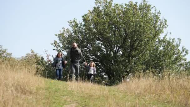 Padre con sus dos hijas corriendo de la colina a cámara . — Vídeos de Stock