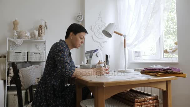 Vrouw werkt met naaiende patronen op een studio-tafel. — Stockvideo