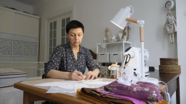 Жінка працює з шиттям візерунків на студійному столі . — стокове відео