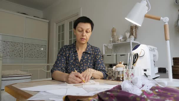 Mujer está trabajando con patrones de costura en una mesa de estudio . — Vídeos de Stock