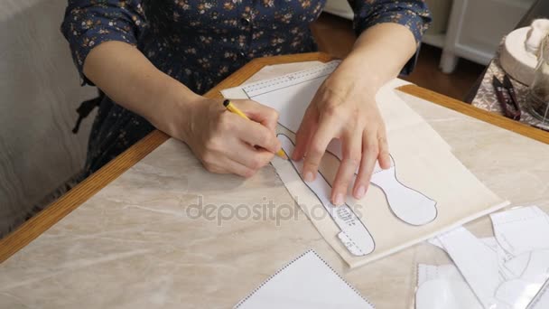 Womans hand is working with sewing patterns on a studio table. — Stock Video