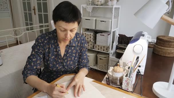Женщина работает с шаблонами шитья на студийном столе . — стоковое видео