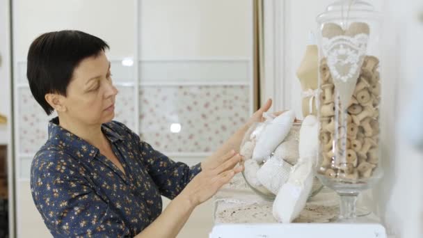 Woman comes to the shelving and selects ribbons from the vase bowl aquarium — Stock Video