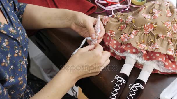 Le mani delle donne cuciono il dettaglio dei vestiti per la bambola. Vista dall'alto. Primo piano . — Video Stock