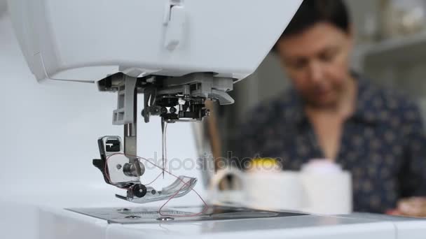 Primo piano di una macchina da cucire sullo sfondo di una donna che cuce — Video Stock