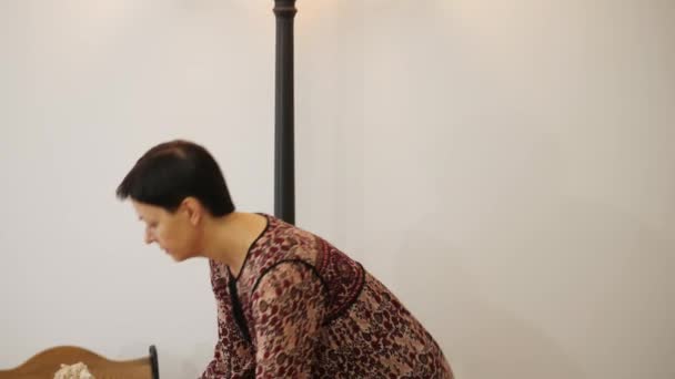 Μια γυναίκα βάζει μια όμορφη κούκλα σε μια καρέκλα — Αρχείο Βίντεο
