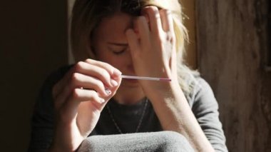 Pencere pozitif gebelik testi sonucu hakkında oturup ağlayan kadın