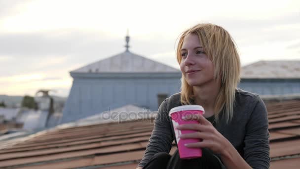 Joven mujer feliz se sienta con café en la azotea. Viento soplando su pelo . — Vídeos de Stock