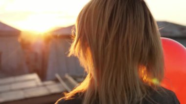 Kadın balon ile çatı katında yürüyen mutlu hissediyor. Arkadan Görünüm.