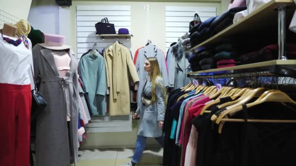 Две девушки выбирают пальто в магазине . — стоковое видео